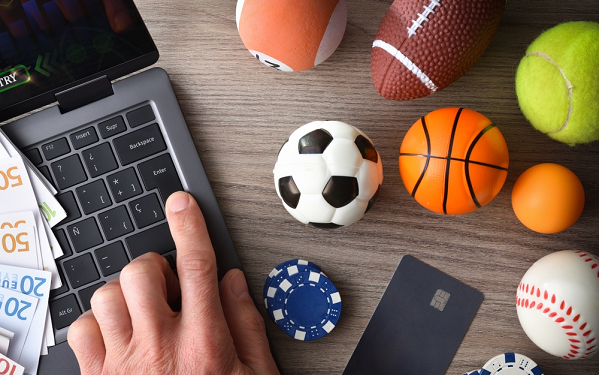 Laptop next to various sports equipment and poker chips