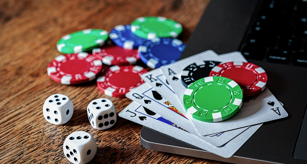 poker chips, dice and cards next to laptop on table