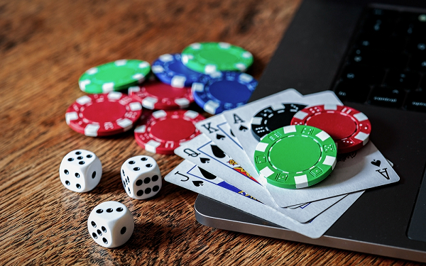poker chips, dice and cards next to laptop on table